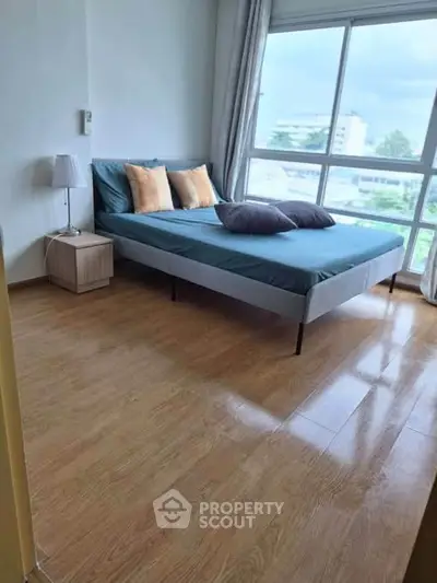Bright bedroom with large window and modern furnishings, offering a serene and inviting atmosphere.