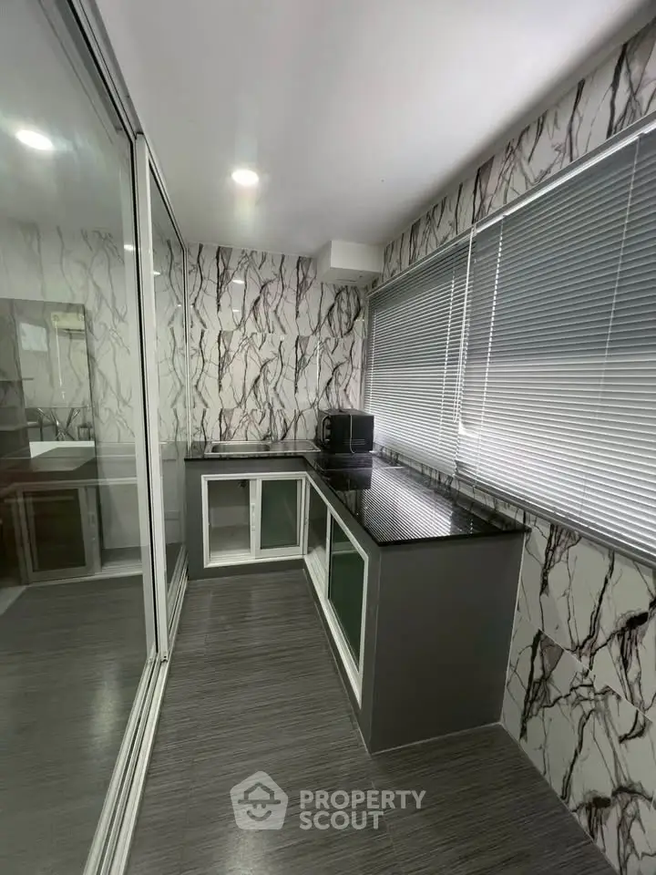 Modern kitchen with sleek countertops and marble-patterned walls