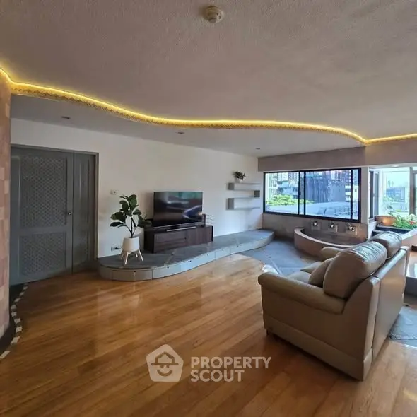 Spacious living room with modern decor and large windows offering city views.