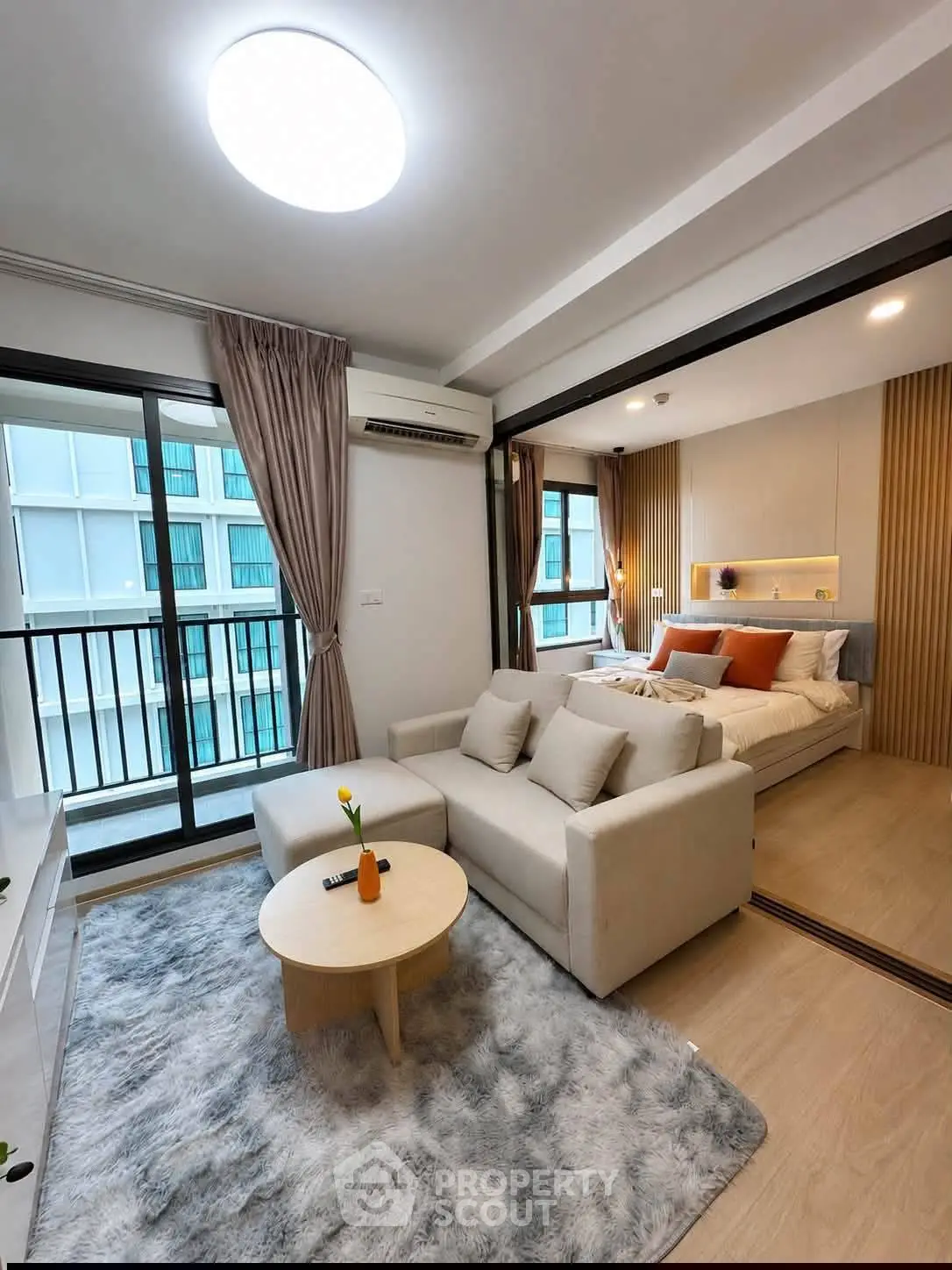 Modern studio apartment with cozy living area and stylish bedroom, featuring a balcony with city views.