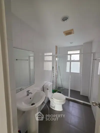 Modern bathroom with glass shower and sleek fixtures in a bright, tiled space.