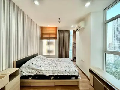 Spacious bedroom with modern decor and large windows offering city views.