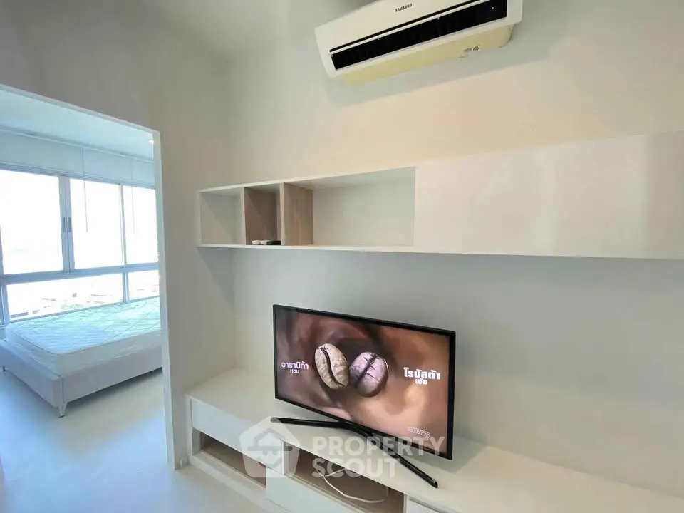 Modern apartment interior with wall-mounted TV and air conditioning, showcasing sleek design and natural light.