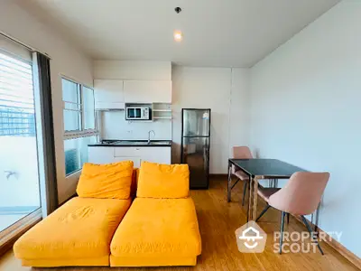 Modern apartment living room with vibrant yellow sofa and sleek kitchen area.