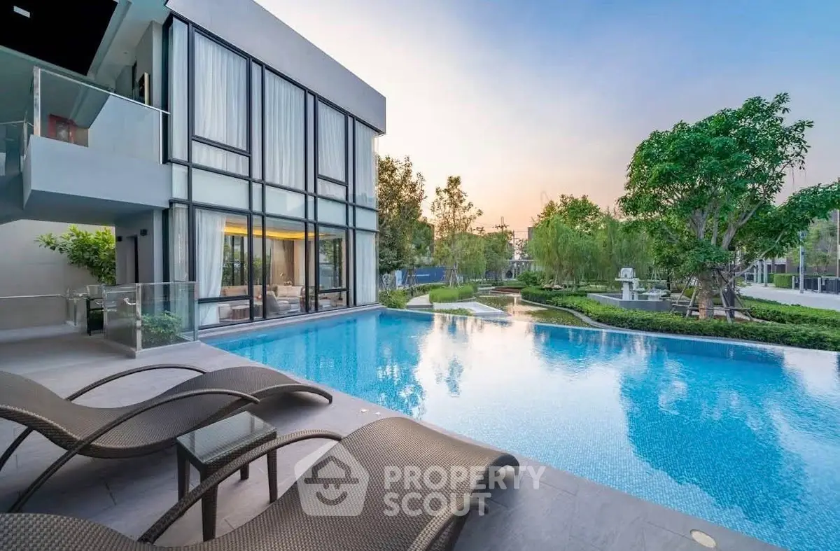 Luxurious modern home with stunning pool and lush garden view at sunset.