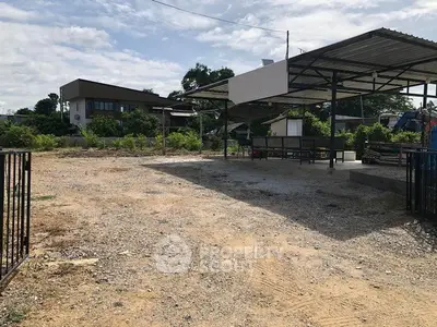 Spacious outdoor area with covered structure and gravel surface, ideal for development or parking.