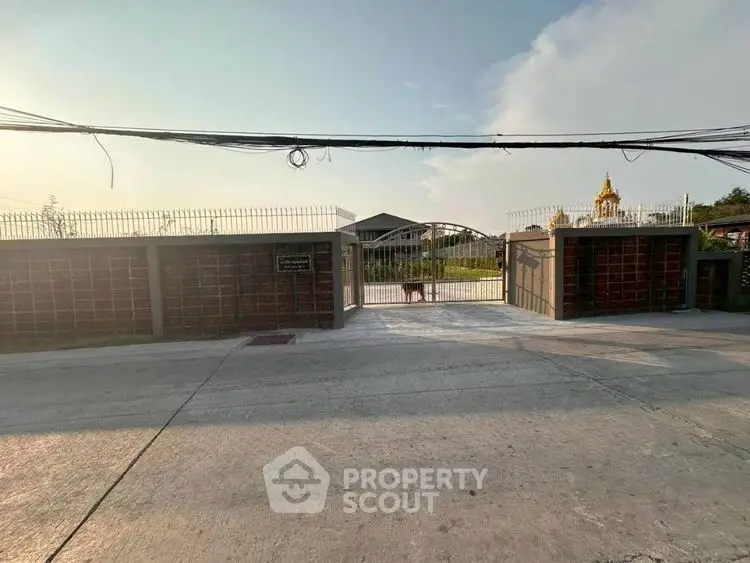 Secure gated entrance to a residential property with clear sky backdrop.