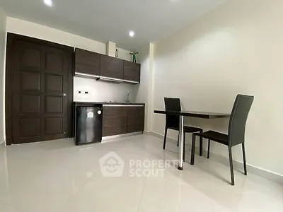 Modern minimalist kitchen with sleek cabinetry and dining area.