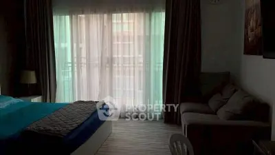 Cozy bedroom with balcony access and natural light through sheer curtains.