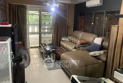 Cozy living room with large leather sofa and sliding glass doors leading to a spacious balcony.