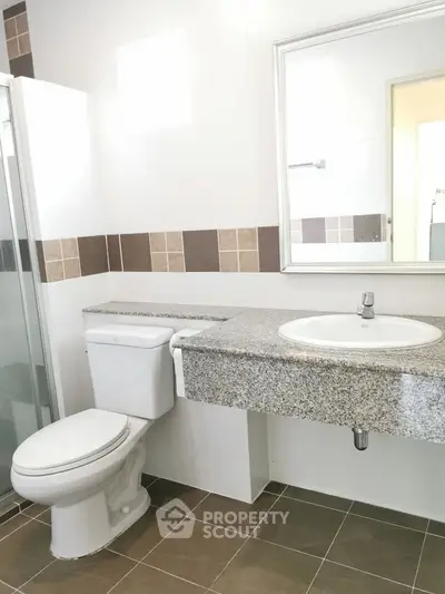 Modern bathroom with granite countertop and tiled shower in elegant real estate property.