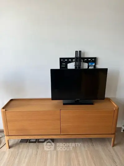 Modern wooden TV stand with mounted flat-screen TV in minimalist living room.