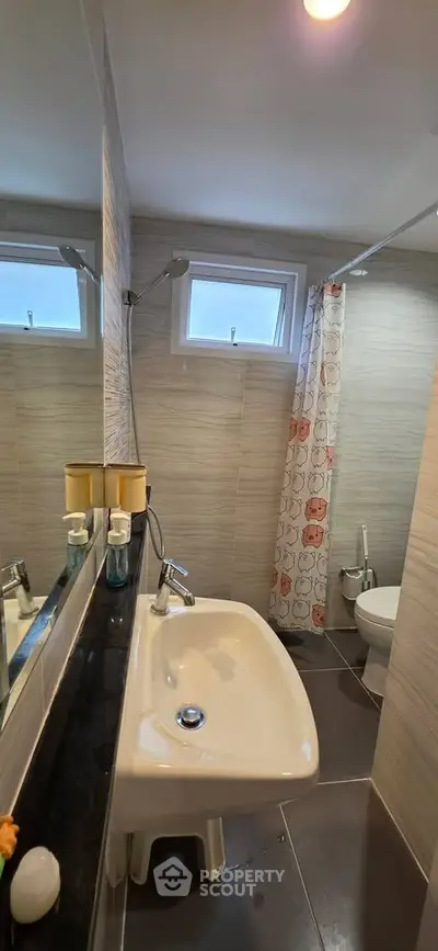Modern bathroom with sleek fixtures and stylish shower curtain in a cozy apartment.