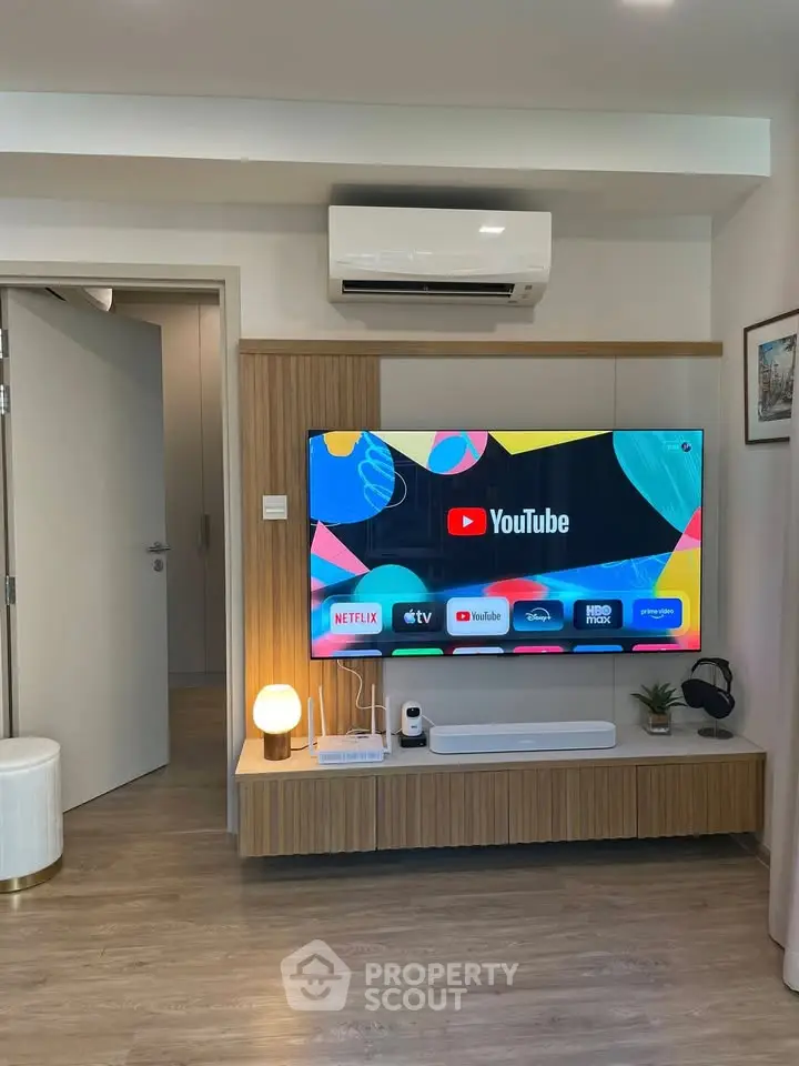 Modern living room with smart TV and air conditioning, showcasing sleek design and cozy ambiance.