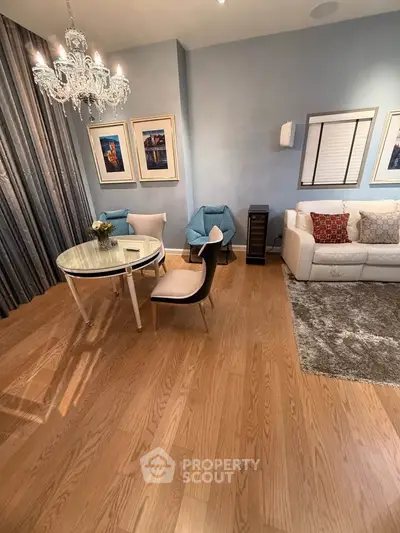 Elegant living room with hardwood floors, stylish furniture, and a chic chandelier for a cozy ambiance.