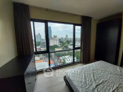 Spacious bedroom with stunning city view from large windows in modern apartment.