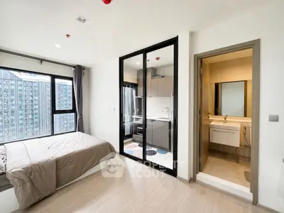 Modern studio apartment with bedroom, kitchenette, and bathroom, featuring large windows and sleek design.