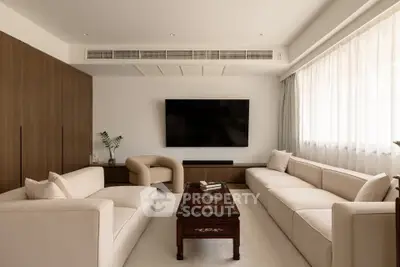 Elegant living room with modern furniture and large TV, featuring a cozy ambiance and natural light.