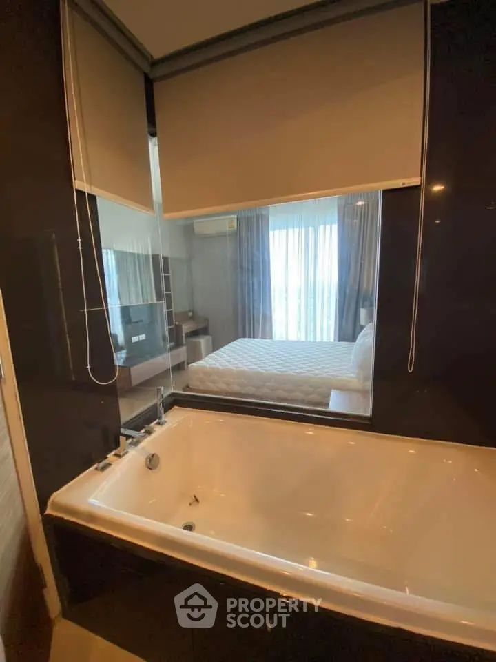 Luxurious bathroom with bathtub and view into modern bedroom