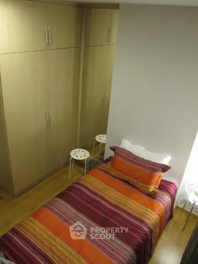 Cozy bedroom with vibrant striped bedding and built-in wardrobe