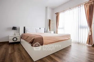 Spacious bedroom with elegant decor and large window for natural light.