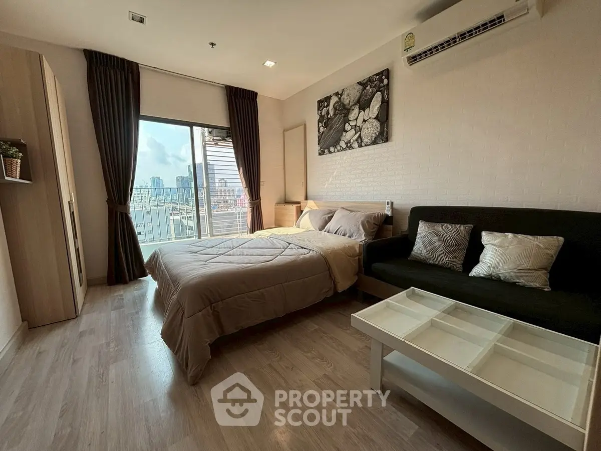 Modern bedroom with city view, featuring cozy bed, stylish decor, and large window for natural light.