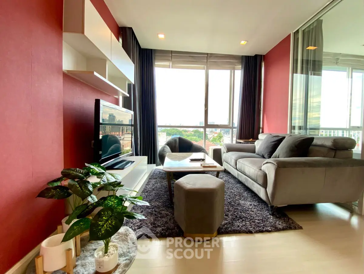 Stylish modern living room with red accent wall and large windows offering natural light.