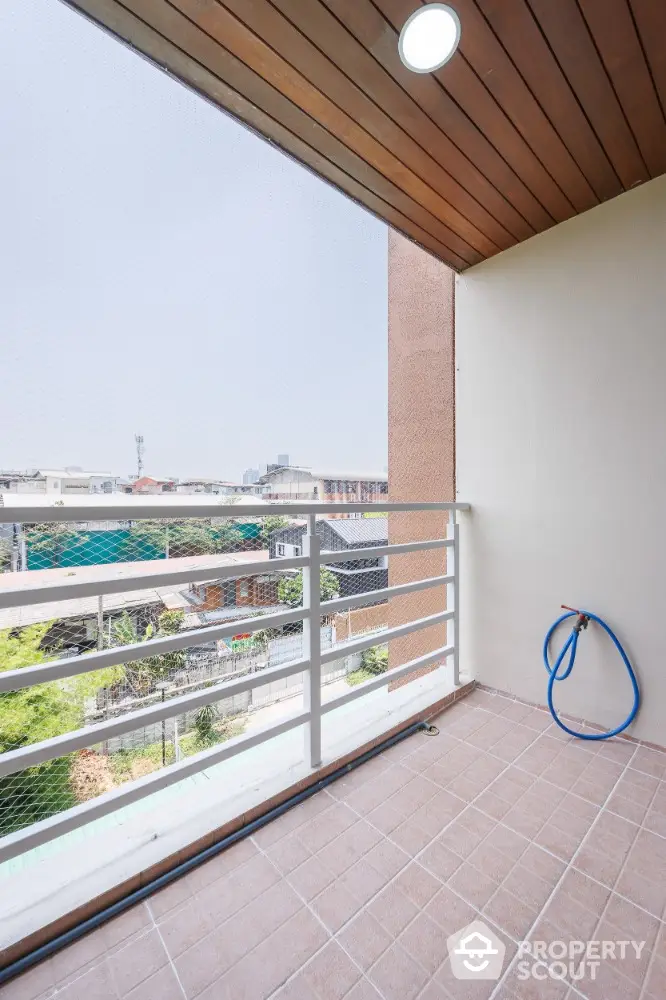 Spacious balcony with city view and tiled flooring in modern apartment.