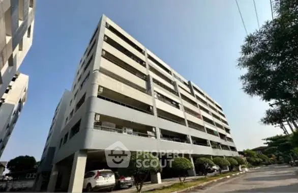 Modern multi-story apartment building with ample parking and lush greenery, ideal for urban living.