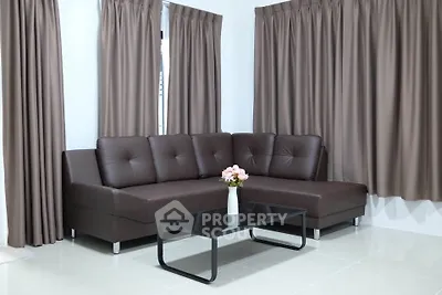 Modern living room with sleek brown sectional sofa and elegant curtains.