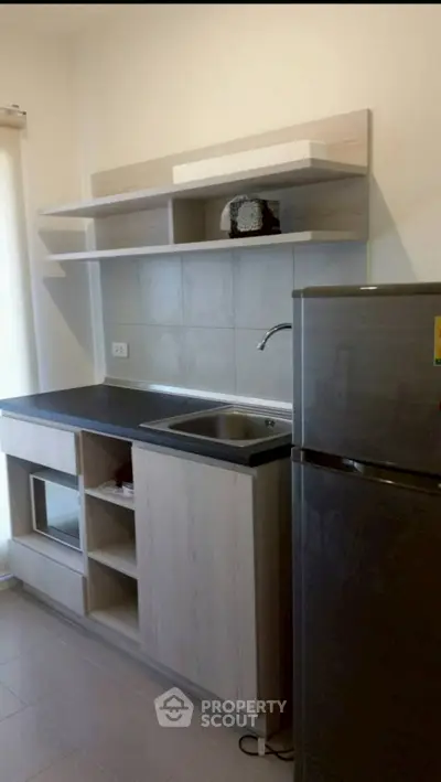 Modern kitchen with sleek cabinetry and stainless steel fridge in a compact layout.