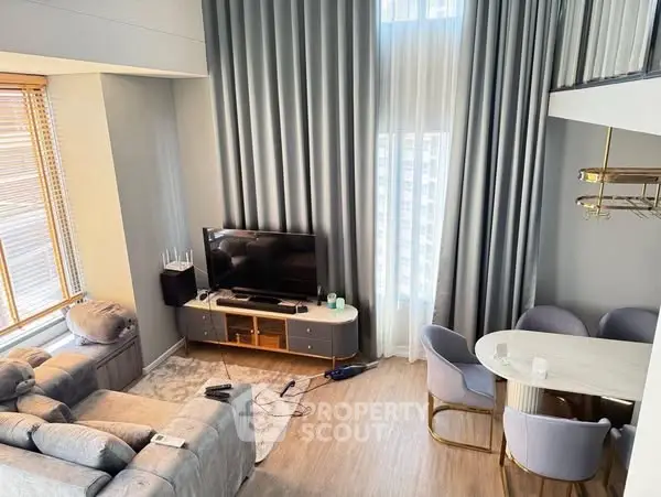 Modern living room with high ceilings, elegant curtains, and cozy seating area.