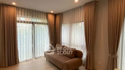 Elegant living room with floor-to-ceiling windows and plush sofa, featuring luxurious curtains.