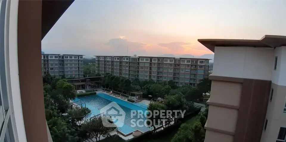 Stunning sunset view of modern apartment complex with pool and lush greenery.