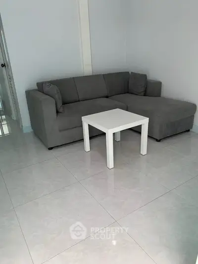 Modern living room with sleek gray sofa and minimalist white table on glossy tiled floor.