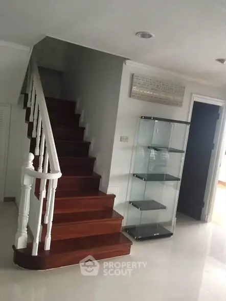 Elegant staircase with wooden steps and glass shelving in modern home interior