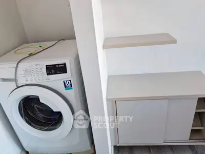 Modern laundry area with washing machine and storage shelves in a sleek apartment.