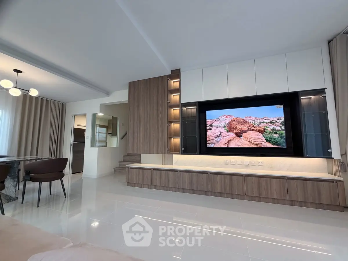 Modern living room with sleek TV unit and dining area, showcasing elegant interior design.