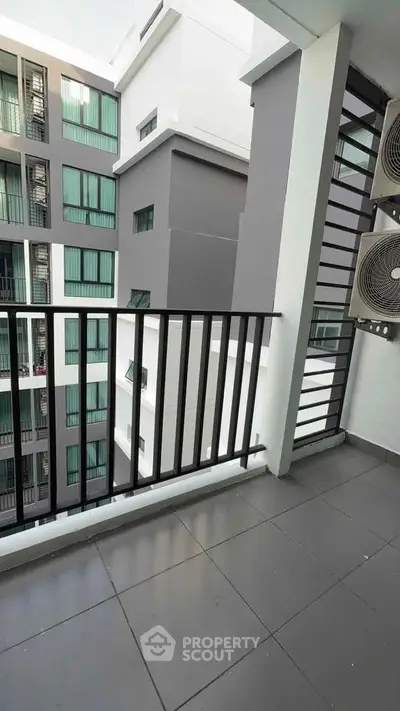 Modern apartment balcony with sleek railing and air conditioning units, offering urban views.