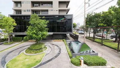 Modern building exterior with landscaped entrance and water feature in urban setting.