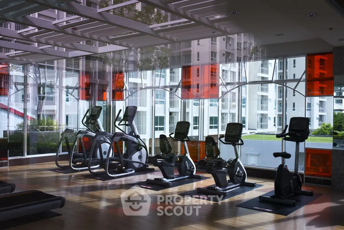 Modern gym with state-of-the-art exercise equipment and large windows offering a bright, inviting atmosphere.
