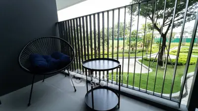 Modern balcony with stylish furniture overlooking lush green garden in luxury apartment.
