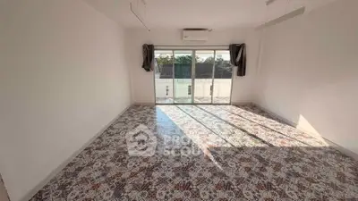 Spacious empty room with patterned tile flooring and large windows offering natural light.