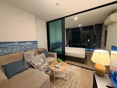 Modern living room with cozy seating and view into a stylish bedroom through glass partition.