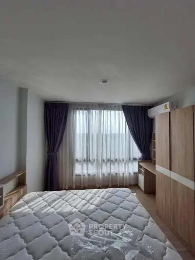 Bright bedroom with large window and modern wooden furniture, perfect for cozy living.