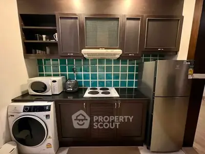 Modern kitchen with dark wood cabinets, green tile backsplash, and stainless steel appliances.