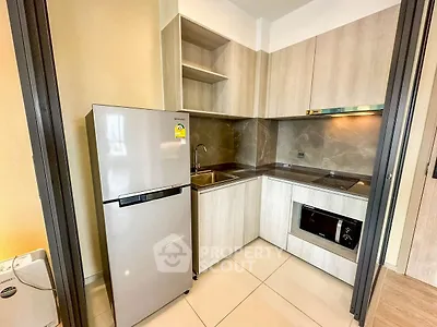 Modern kitchen with sleek cabinets, stainless steel fridge, and built-in oven in a compact layout.