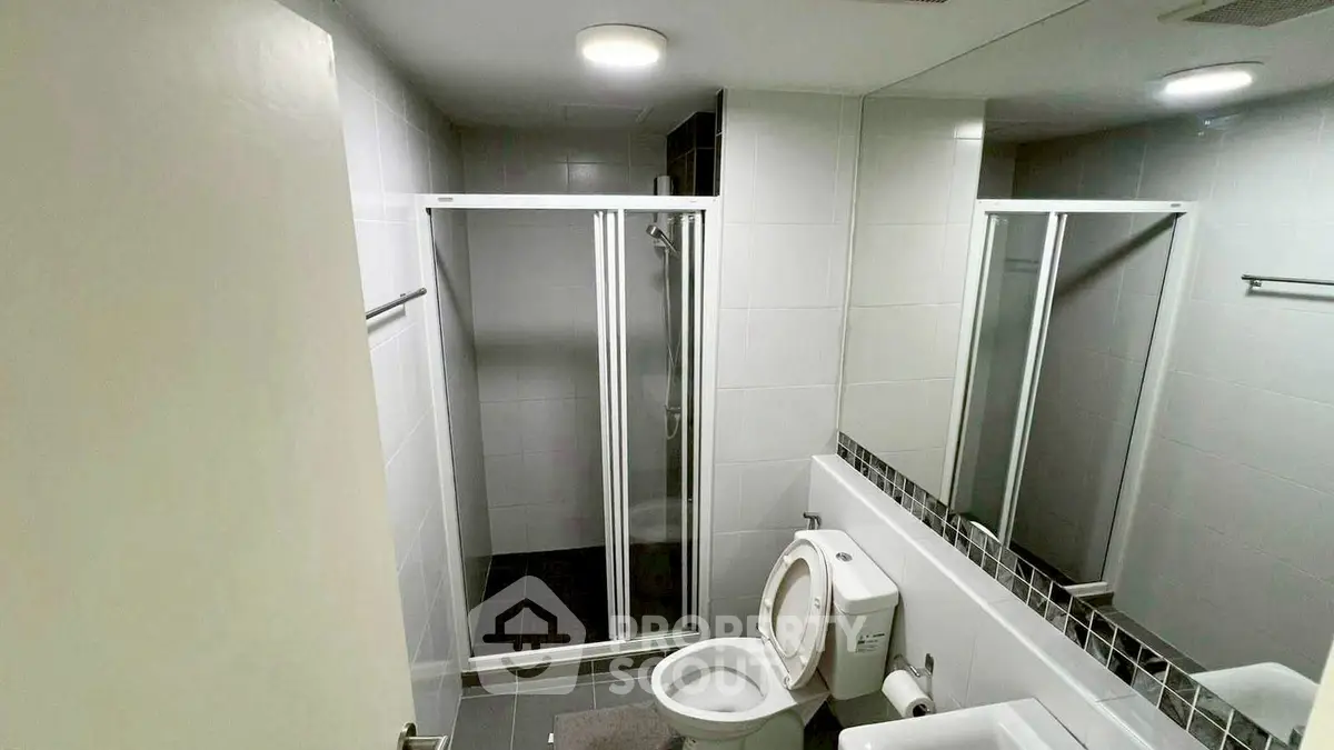 Modern bathroom with sleek shower and white fixtures in a contemporary apartment.