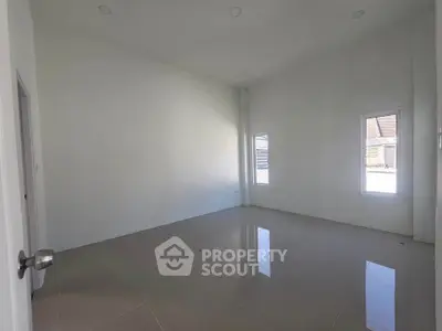 Spacious empty room with high ceiling and large windows, perfect for customization.
