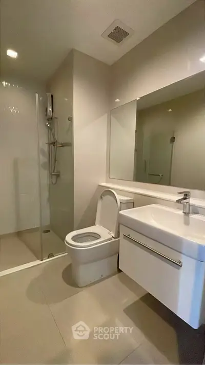 Modern bathroom with sleek fixtures and spacious shower in contemporary apartment.
